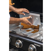 Eine Person setzt eine Edelstahlplatte in einen Gasgrill ein.