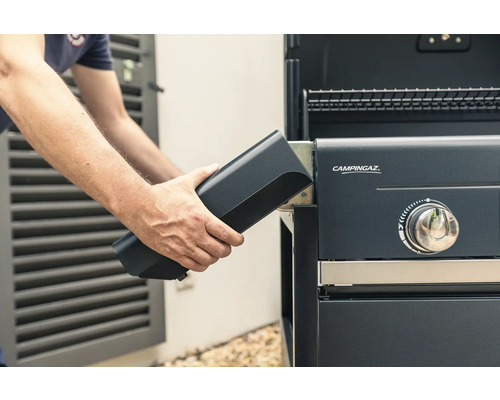 Person setzt Batterie in Gasgrill ein