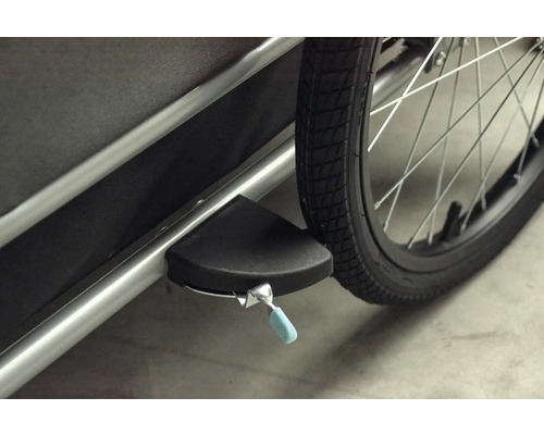 Detailansicht eines Fahrradanhängers mit Feststellbremse und Rad