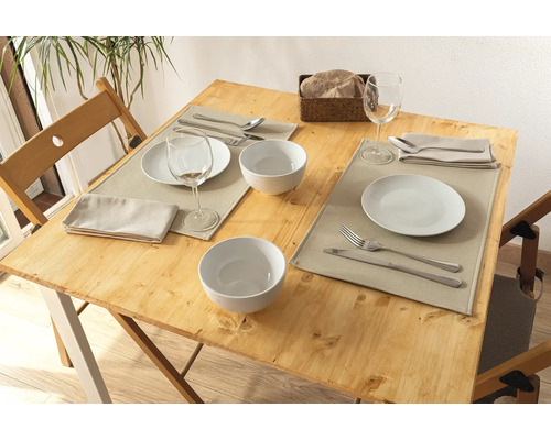 Gedeckter Holztisch mit Tellern, Schüsseln, Besteck, Servietten und Tischsets für zwei Personen