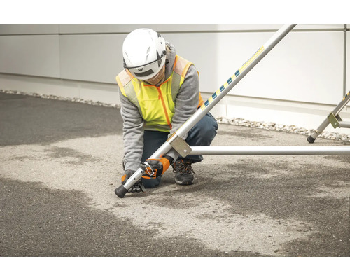 Eine Person montiert ein Baugerüst mit Nivellierfüßen.