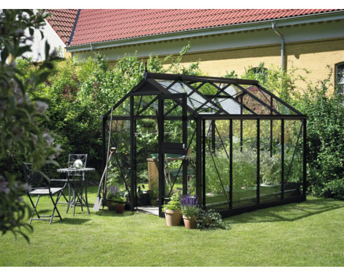 Gewächshaus im Garten mit Tisch und Stühlen.