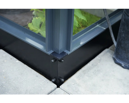 Detailansicht einer Gewächshausecke mit Aluminiumrahmen und Fundament auf Steinplatten