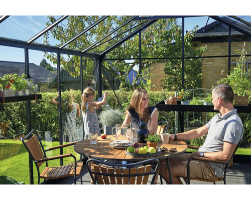 Familie entspannt sich in einem Gewächshaus mit Tisch und Stühlen