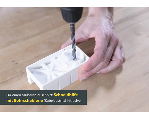 Eine Person bohrt mit einer Bohrmaschine in eine Bohrschablone.