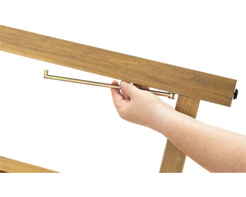 Detailaufnahme einer Person, die einen Metallstift in einen Holzrahmen einführt