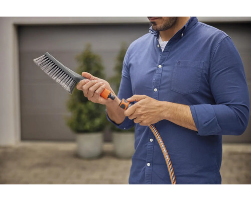 Mann schließt Bürste an Gartenschlauch an