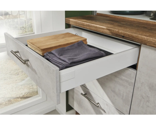 Küchenschrank mit offener Schublade, darin ein Schneidebrett und ein Geschirrtuch