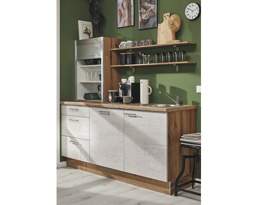 Küchenzeile mit Spüle, Schränken und Regalen an einer grünen Wand