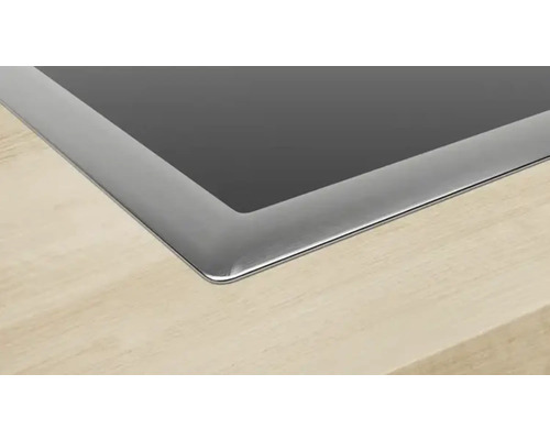 Detailansicht eines Kochfeldes mit Edelstahlrahmen auf einer Arbeitsplatte.