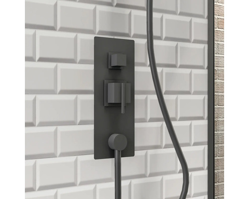 Schwarze Duscharmatur an einer weißen Wand mit rechteckigen Fliesen