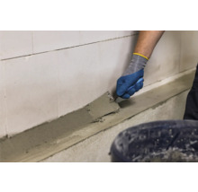 Handwerker trägt Mörtel mit einer Kelle auf eine Wand auf