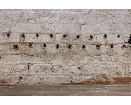 Eine Ziegelwand mit Bohrlöchern.