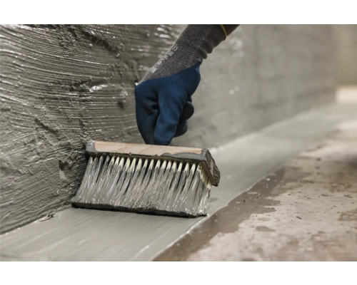 Auftragen einer Dichtungsschlämme mit einem Quast auf einer Wand