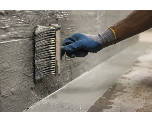 Auftragen von Dichtschlämme mit Flächenstreicher auf Wand und Boden