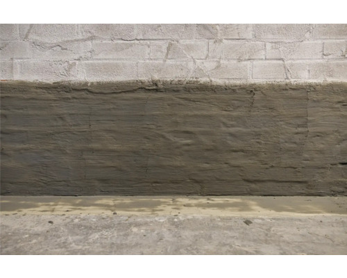 Betonwand mit Feuchtigkeitssperre im unteren Bereich.
