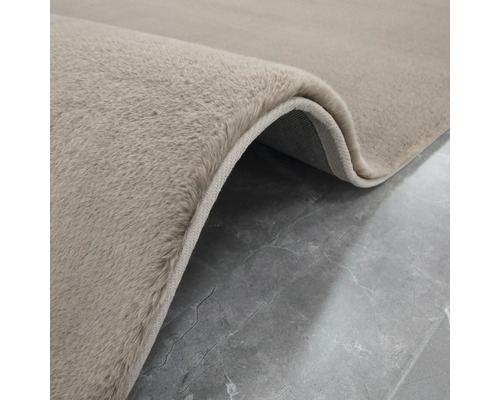 Detailansicht eines beigen Teppichs mit hochflorigem Flor.