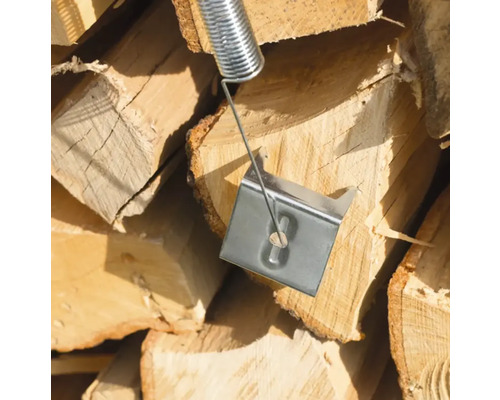 Holzspalterfeder vor einem Stapel Brennholz