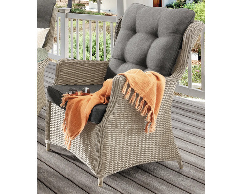 Korbsessel mit Sitz- und Rückenkissen sowie einer Decke auf einer Terrasse