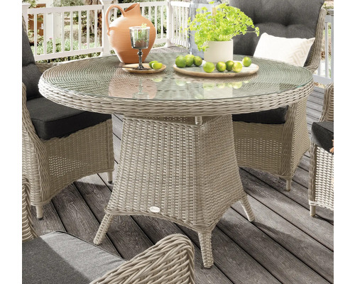 Runder Gartentisch mit Glasplatte und Rattanoptik, umgeben von Stühlen auf einer Terrasse