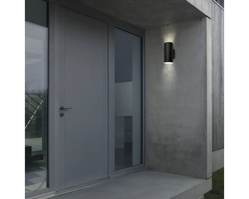 Moderne Außenwandleuchte neben einer Tür an einer Betonwand