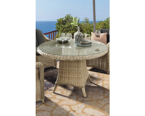 Gartenszene mit rundem Esstisch aus Rattan mit Glasplatte