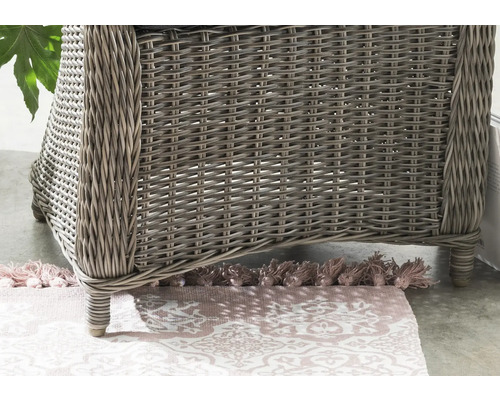 Detailansicht eines Korbsessels mit geflochtener Oberfläche und einem gemusterten Teppich