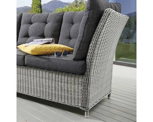 Nahaufnahme eines grauen Rattansofas mit Kissen auf einer Terrasse
