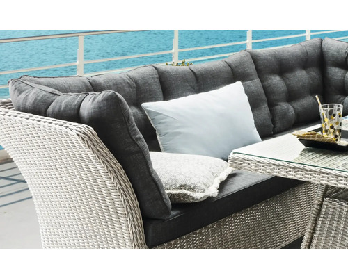 Detailansicht einer Rattansitzgruppe mit Polstern und Kissen auf einer Terrasse mit Meerblick