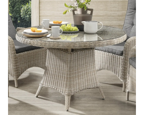 Runder Gartentisch mit Glasplatte und Rattanstruktur mit Speisen und Getränken gedeckt