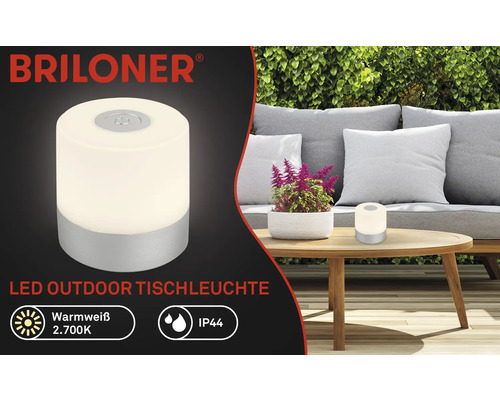 Briloner Logo. LED-Tischleuchte für den Außenbereich auf einem Tisch im Garten.