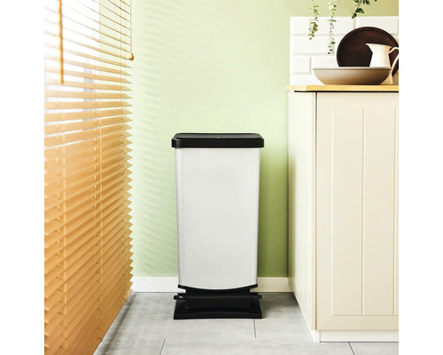 Weißer Treteimer mit schwarzem Deckel und Fußpedal in einer Küche.