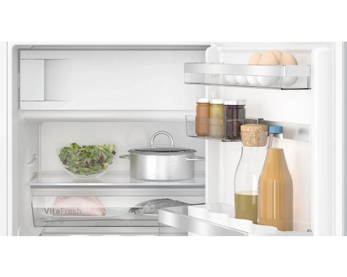 Innenraum eines Kühlschranks mit Lebensmitteln wie Eiern, Salat und Getränken