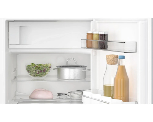 Innenraum eines Kühlschranks mit Lebensmitteln wie Salat, Marmelade und Getränken