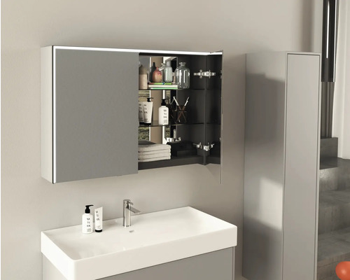 Badezimmer mit Waschbecken, Armatur und geöffnetem Spiegelschrank mit Beleuchtung