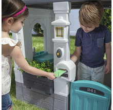 Kinder spielen mit einem Spielhaus mit Briefkasten und Spüle