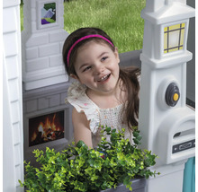 Mädchen im Spielhaus mit Briefkasten, Klingel, Kamin und Fensterbild