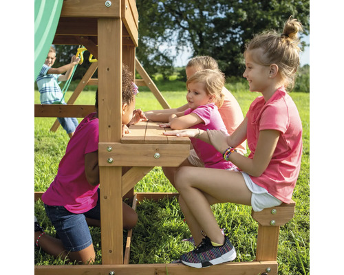 Kinder spielen auf einem Spielturm mit Tisch und Bänken im Garten.