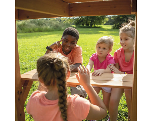 Kinder sitzen an einem Holztisch im Freien und interagieren miteinander.