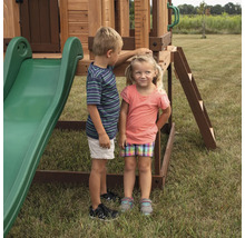 Zwei Kinder stehen neben einem Spielplatzgerät mit Rutsche und Leiter im Garten.