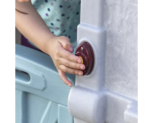 Nahaufnahme eines Kindes, das einen Knopf an einem Spielhaus drückt.