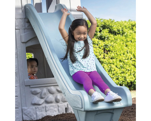 Mädchen rutscht auf einer Kinderrutsche im Garten.