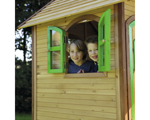 Zwei Kinder schauen aus dem Fenster eines Holzspielhauses