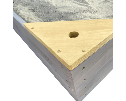 Detailansicht eines Sandkastens mit Holzabdeckung und Sand