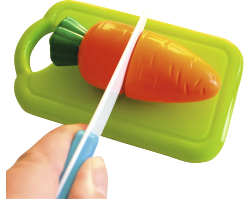 Spielzeug-Messer schneidet Spielzeug-Karotte auf einem Spielzeug-Schneidebrett