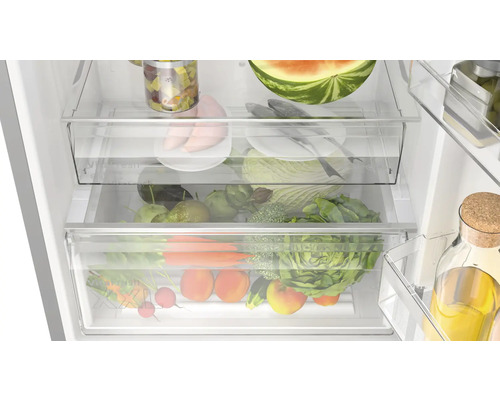 Innenansicht eines Kühlschranks mit transparenten Schubladen gefüllt mit verschiedenen Lebensmitteln wie Gemüse, Obst und Fleisch.