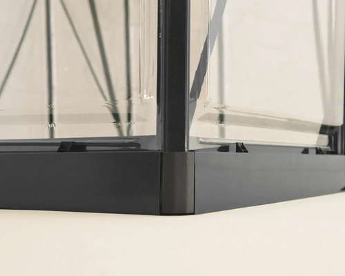 Detailansicht eines Gewächshauses mit Metallrahmen und Glasplatten.