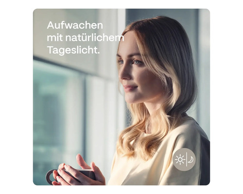 Frau mit einer Tasse am Fenster mit natürlichem Tageslicht