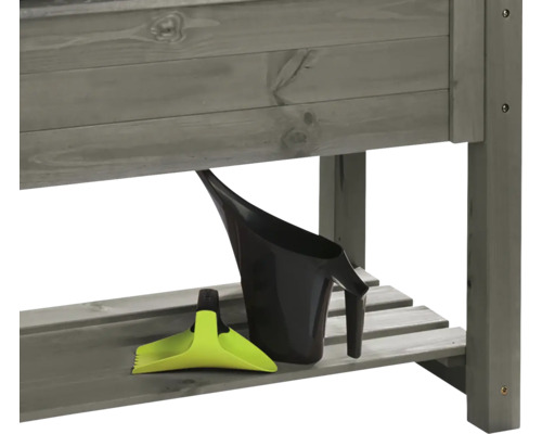 Detailansicht eines Gartentisches mit Gießkanne und Pflanzschaufel auf der Ablage