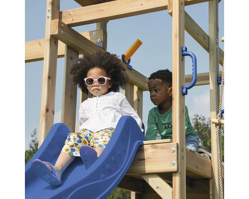 Kinder spielen auf einem Spielplatz mit Rutsche, Kletterwand und Schaukel